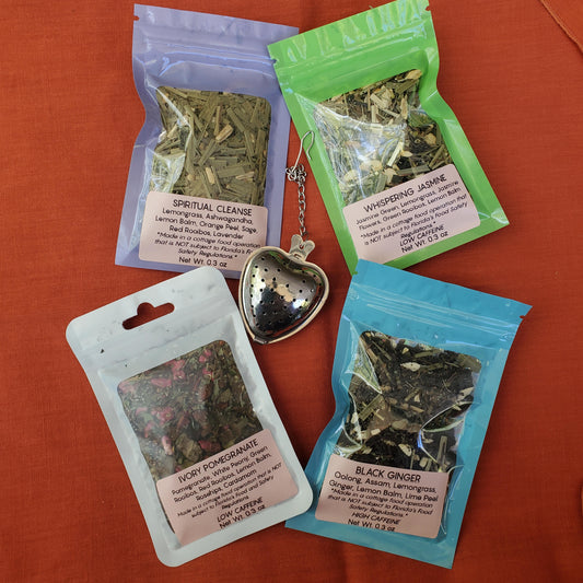 Four packages of dried herbs on an orange surface with a heart-shaped pendant.